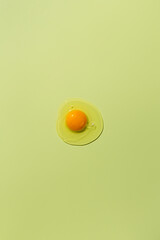 Raw egg yolk on a green background. View from above