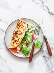 Oatmeal omelet with avocado, tomatoes, green salad and cream cheese on a light background, top view