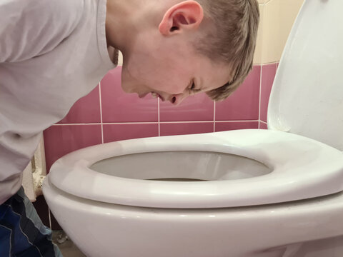 Sick boy child vomits and vomits, vomits into toilet