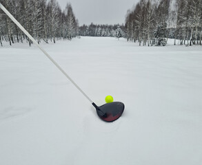 Closeup of golf ball and club in snow