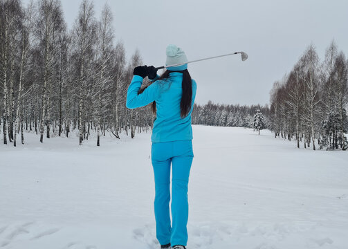 Female golfer plays golf on golf course in winter