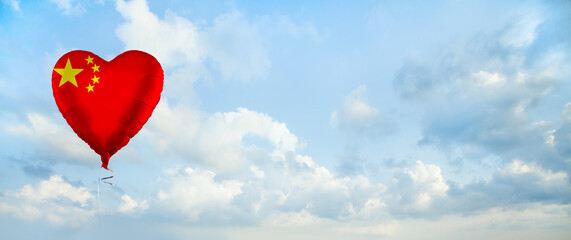 Flag of China on heart-shaped balloon against sky clouds background. Education, charity,...