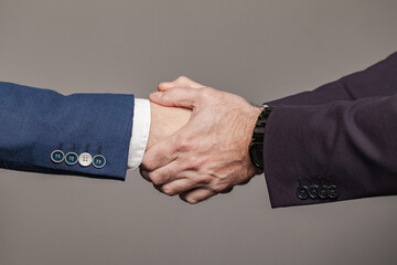 Business people in suit shaking hands, completed deal concept on grey background