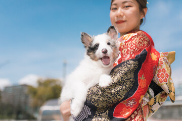 楽しそうに笑う赤い振袖を着た女性と白毛の犬