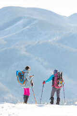 two girls stand on top of a mountain and take pictures of nature. hike in winter.