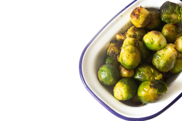 Brussels sprouts, oven roasted in olive oil,  in an enamel dish bowl. Isolated on a white background