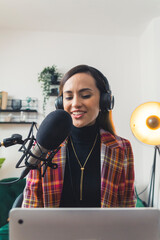 vertical shot of a smiling girl with headphones talking to her guest into a microphone, medium...