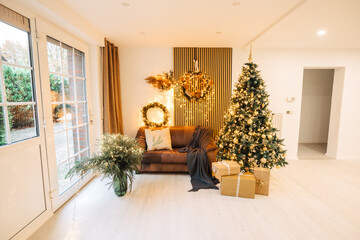Beautiful artificial Christmas tree indoors next to a leather sofa. Beautifully decorated photo studio in Germany with wall panels. Christmas atmosphere in the new house. Acoustic panels in the house