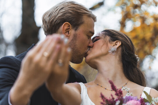 Bride and groom kissing and showing wedding rings on their fingers. High quality photo