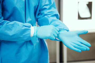 Healthcare, scrubs and surgeon hands with gloves for protection in surgery, medical operation and procedure. Safety, doctor and health worker with latex ppe in clinic, hospital and operating room