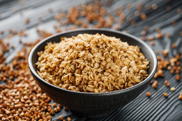 fresh raw buckwheat flakes on a black wooden background