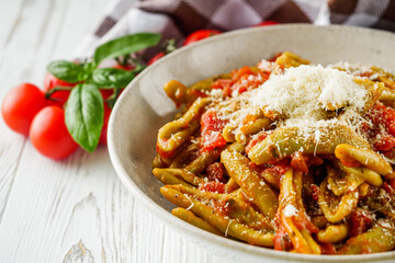 green cavatelli pasta with spinach in tomato sauce on a white wooden background