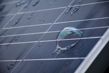 The front surface of photovoltaic or solar cell panel which is wet with water and soap bubbles on...