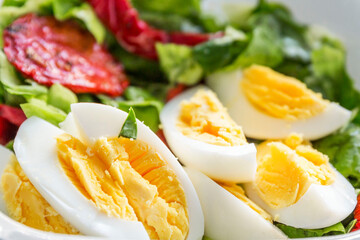 Halves of boiled eggs with lettuce and sun-dried tomatoes. Healthy food and vitamins. Close-up.