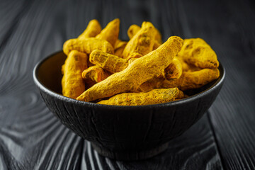 aromatic turmeric root on a black wooden rustic background
