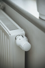 Close-up of a thermostat on the heating radiator. Heater regulator in the modern white interior. Temperature knob