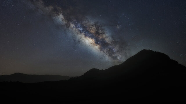 panorama mountain silhouette and blue night sky milky way and star on dark background. universe called,nebula and galaxy with noise and grain. Cassiopeia is a constellation in the northern sky. 