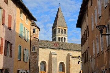 The external facade of Saint Philibert Abbey Church in Tournus, Burgundy, France, with historical house facades in the foreground. Picture taken from Fenelon street.