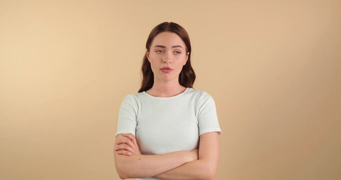 Displeased young woman crossing arms on beige background