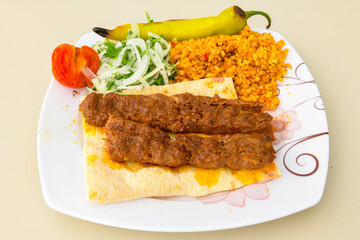 Grilled Turkish Adana, Urfa  Kebab with grilled vegetables, onion and rice on plate. Adana durum.