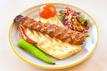 Grilled Turkish Adana, Urfa  Kebab with grilled vegetables, onion and rice on plate. Adana durum.