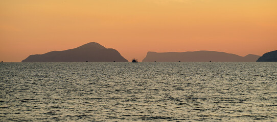 Fototapeta na wymiar Tisan Dana Island in sunset and some boats seem barely far away, selective focus, Mersin Turkey
