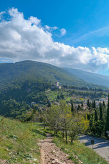 The descent overlooking the mountains, Italian houses in the distance, and cypresses.