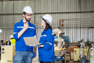 A team of male and female engineers meeting to inspect computer-controlled steel welding robots. Plan for rehearsals and installation for use.
