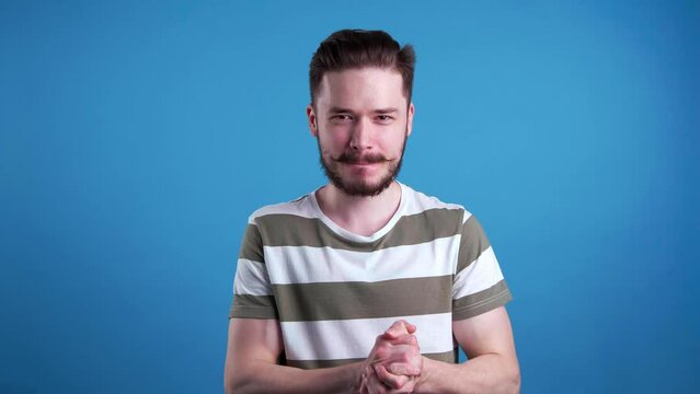 Mischievous young man rubbing hands on light blue background