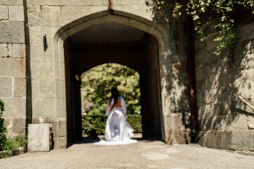 Fototapeta na wymiar a beautiful woman in a white dress walks through a beautiful palace on a sunny day
