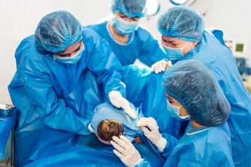 Professional anesthesiologist doctor medical team and assistant is performing baby cesarean section and hold the baby giving birth with surgery equipment in modern hospital operation room