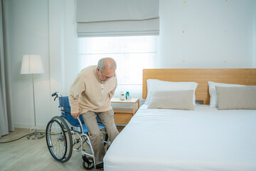 Senior man are using wheelchair for motion after doing physical therapy alone at home.