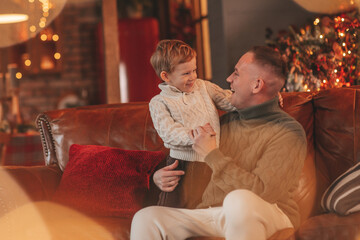 Candid authentic happy dad playing with little son fooling around at wooden lodge Xmas decorated