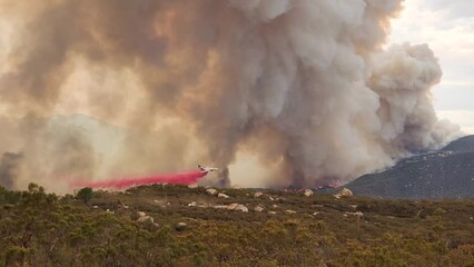 Footage of wildfire and billowing smoke as airplane flies low to do a slurry drop on the raging Fairview Fire in Hemet, California