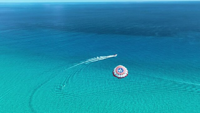 Aerial view following people parasailing on the coast of sunny Cancun, Mexico