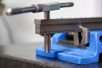 Spiral fluted steel tap bit making a thread in hole on mounted vise,Tapping the workpiece,machine vise