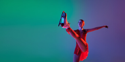 Winter sports. One junior female figure skater in red stage costume showing base figure skating...