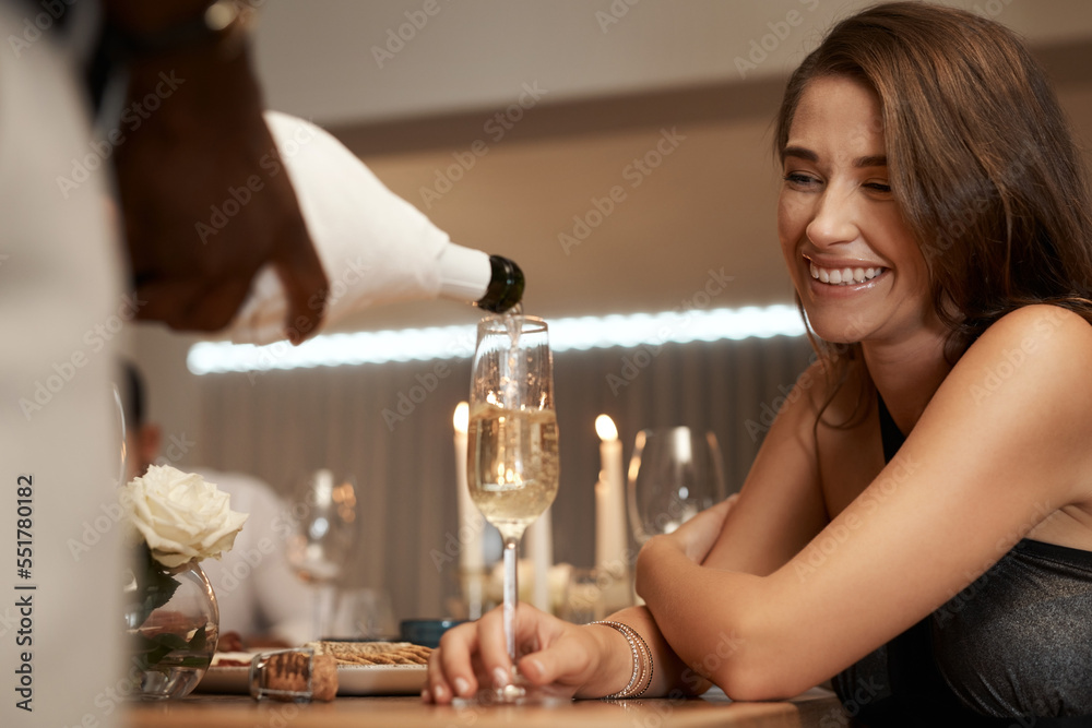 Sticker Happy woman, champagne glass and restaurant with a waiter pouring alcohol for a celebration, birthday or new years event. Female with a smile at table to celebrate holiday with a drink and happiness