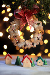 Gingerbread angels on a Christmas tree with a red ribbon hanging over a small town, with houses and Christmas trees, beautiful bokeh.