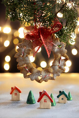 Gingerbread angels on a Christmas tree with a red ribbon hanging over a small town, with houses and...