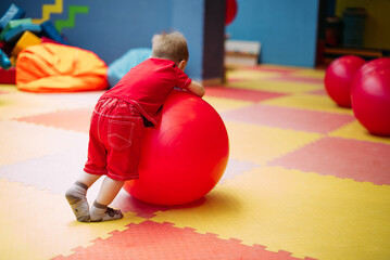 Happy laughing boy 1-2 years old having fun in ball pit  in kids amusement park and indoor play...