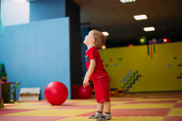 Happy laughing boy 1-2 years old having fun in ball pit  in kids amusement park and indoor play...