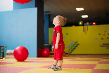 Happy laughing boy 1-2 years old having fun in ball pit  in kids amusement park and indoor play center. Activity toys for little kid