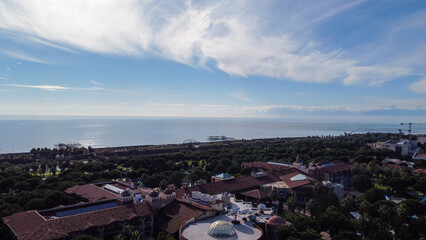 panorama view of sea, sky, clouds, forest and residential area with drone
