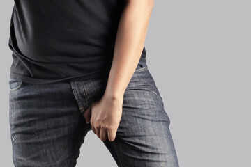 Asian man in reaction of scratching crotch on grey background, closeup. Annoying itch or Tinea...