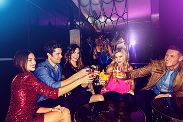 Party, toast and new year with friends in a club, drinking during a celebration event together. Birthday, crowd and cheers with a man and woman friend group enjoying a drink while bonding in a club
