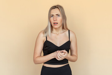 Portrait of dissatisfied young woman. Unhappy girl wearing casual black clothes standing over beige...