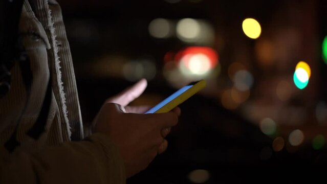 Close up shot with copy space of caucasian man's hands using phone to type and send messages at night in the city.