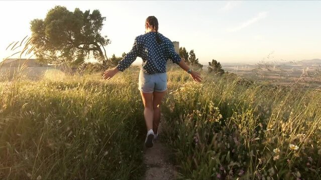 tracking shot of a model running both her hands through the long grass