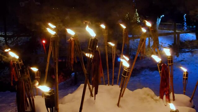 Lots of torches at night with yellow flames and highlights. Embedded in the snow.